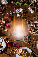 Image showing Early morning after the party. Glasses and plates on the table with confetti and serpentine, leftovers, flower petals