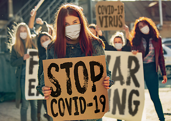 Image showing Young people in face masks protesting of stop coronavirus pandemic on the street