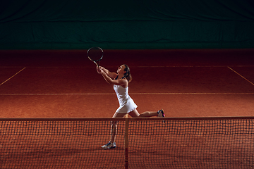 Image showing Young caucasian professional sportswoman playing tennis on sport court background