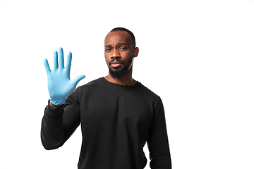 Image showing How coronavirus changed our lives. Young man holding thermometer, taking temperature on white background