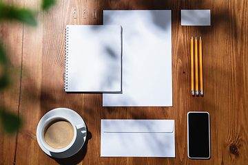 Image showing Creative and cozy workplace at home office, inspirational mock up with plant shadows on table surface