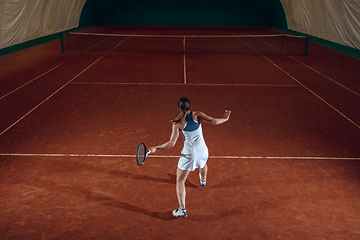 Image showing Young caucasian professional sportswoman playing tennis on sport court background