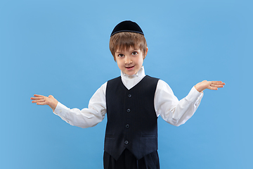Image showing Portrait of a young orthodox jewish boy isolated on blue studio background, meeting the Passover