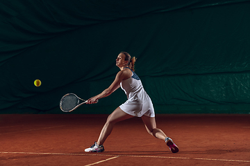 Image showing Young caucasian professional sportswoman playing tennis on sport court background