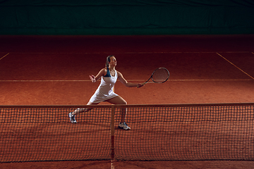 Image showing Young caucasian professional sportswoman playing tennis on sport court background