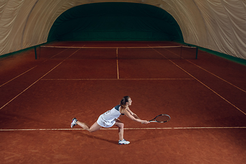 Image showing Young caucasian professional sportswoman playing tennis on sport court background