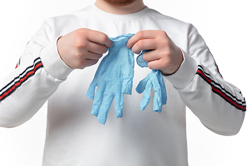 Image showing How coronavirus changed our lives. Young man wearing protective gloves on white background