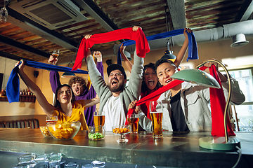 Image showing Sport fans cheering at bar, pub and drinking beer while championship, competition is going