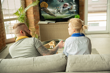 Image showing Excited family watching american football, sport match at home, beautiful couple