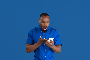 Image showing Monochrome portrait of young african-american man on blue studio background