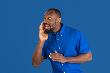 Image showing Monochrome portrait of young african-american man on blue studio background