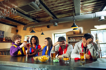 Image showing Sport fans cheering at bar, pub and drinking beer while championship, competition is going