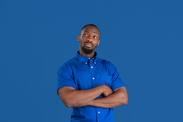 Image showing Monochrome portrait of young african-american man on blue studio background