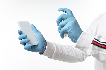 Image showing How coronavirus changed our lives. Young man disinfecting gadgets surfaces on white background