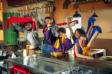 Image showing Sport fans cheering at bar, pub and drinking beer while championship, competition is going