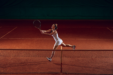 Image showing Young caucasian professional sportswoman playing tennis on sport court background