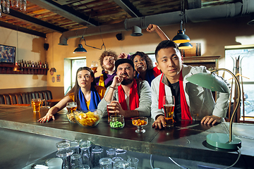 Image showing Sport fans cheering at bar, pub and drinking beer while championship, competition is going