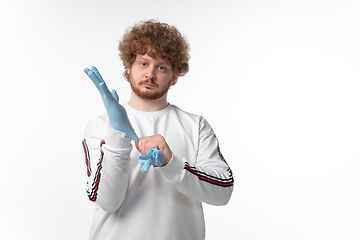 Image showing How coronavirus changed our lives. Young man holding thermometer, taking temperature on white background