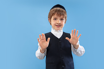 Image showing Portrait of a young orthodox jewish boy isolated on blue studio background, meeting the Passover