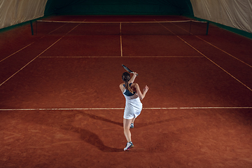 Image showing Young caucasian professional sportswoman playing tennis on sport court background