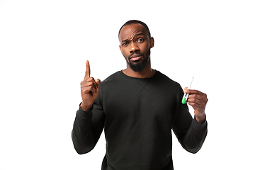 Image showing How coronavirus changed our lives. Young man checking, taking temperature on white background