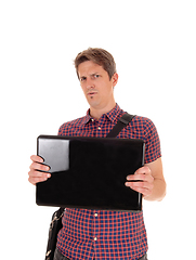 Image showing Puzzled man holding up his laptop to see