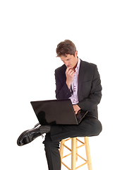 Image showing Puzzled young business man sitting and wondering