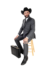 Image showing Business man sitting with hat and briefcase