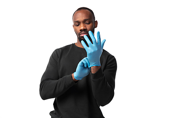 Image showing How coronavirus changed our lives. Young man holding thermometer, taking temperature on white background