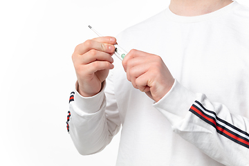 Image showing How coronavirus changed our lives. Close up of male hands holding thermometer, taking temperature on white background