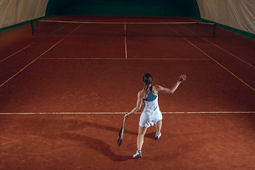 Image showing Young caucasian professional sportswoman playing tennis on sport court background