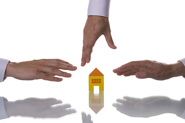 Image showing Three hands trying to reach a house