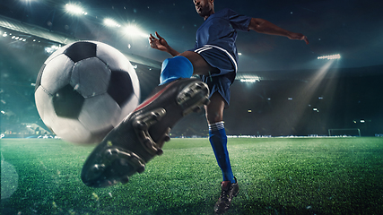 Image showing Football or soccer player in action on stadium with flashlights, kicking ball for winning goal, wide angle