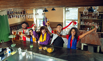 Image showing Sport fans cheering at bar, pub and drinking beer while championship, competition is going