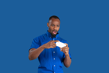 Image showing Monochrome portrait of young african-american man on blue studio background