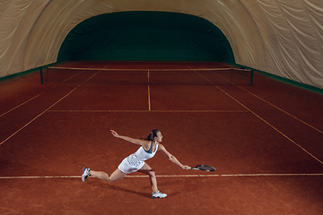 Image showing Young caucasian professional sportswoman playing tennis on sport court background