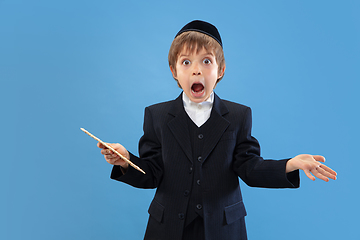 Image showing Portrait of a young orthodox jewish boy isolated on blue studio background, meeting the Passover