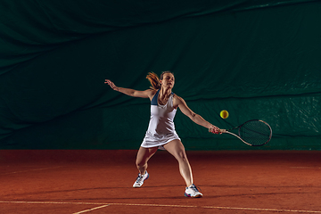 Image showing Young caucasian professional sportswoman playing tennis on sport court background