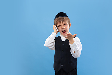 Image showing Portrait of a young orthodox jewish boy isolated on blue studio background, meeting the Passover