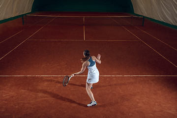 Image showing Young caucasian professional sportswoman playing tennis on sport court background