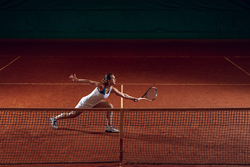 Image showing Young caucasian professional sportswoman playing tennis on sport court background