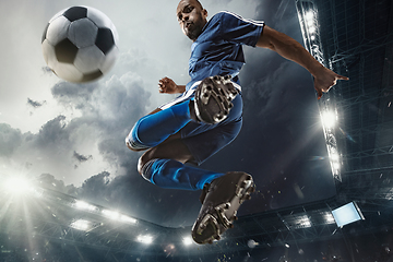 Image showing Football or soccer player in action on stadium with flashlights, kicking ball for winning goal, wide angle