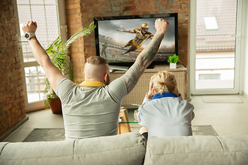Image showing Excited family watching american football, sport match at home, beautiful couple