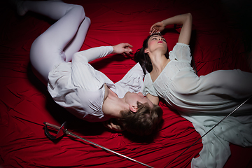 Image showing Young and graceful ballet dancers on billowing red cloth background in classic action. Art, motion, action, flexibility, inspiration concept.