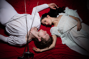 Image showing Young and graceful ballet dancers on billowing red cloth background in classic action. Art, motion, action, flexibility, inspiration concept.