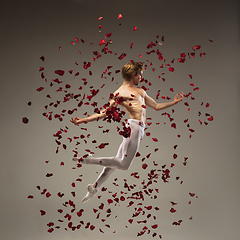 Image showing Young and graceful ballet dancer on studio background with rose petals. Art, motion, action, flexibility, inspiration concept.