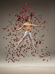 Image showing Young and graceful ballet dancer on studio background with rose petals. Art, motion, action, flexibility, inspiration concept.