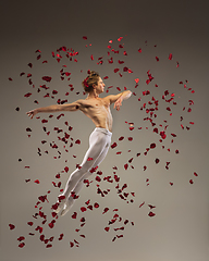 Image showing Young and graceful ballet dancer on studio background with rose petals. Art, motion, action, flexibility, inspiration concept.