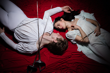 Image showing Young and graceful ballet dancers on billowing red cloth background in classic action. Art, motion, action, flexibility, inspiration concept.