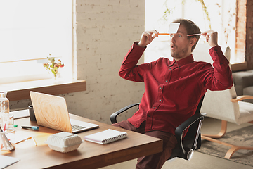 Image showing Caucasian entrepreneur, businessman, manager trying to work, looks funny, lazy and spending time